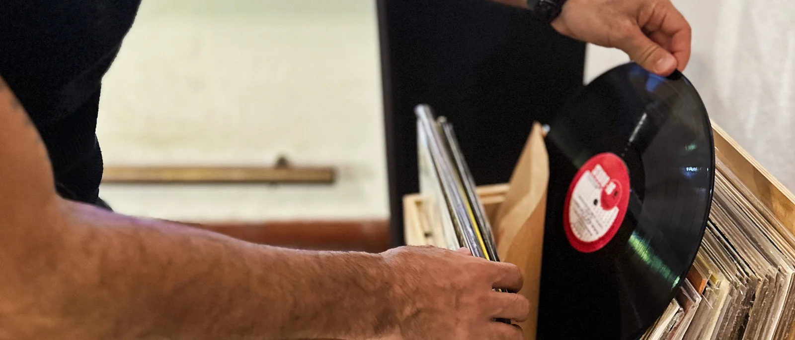 Manos eligiendo un vinilo del cajón de discos del living.