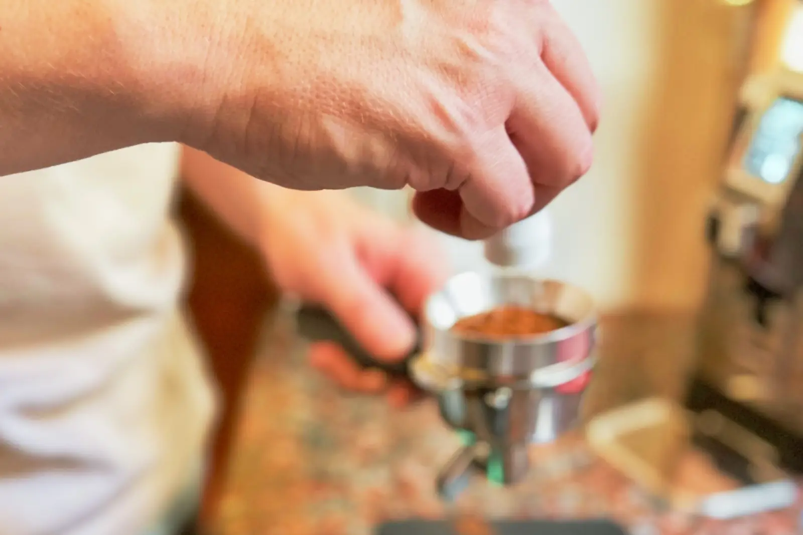 A hand preparing an espresso: ground coffee in the portafilter.